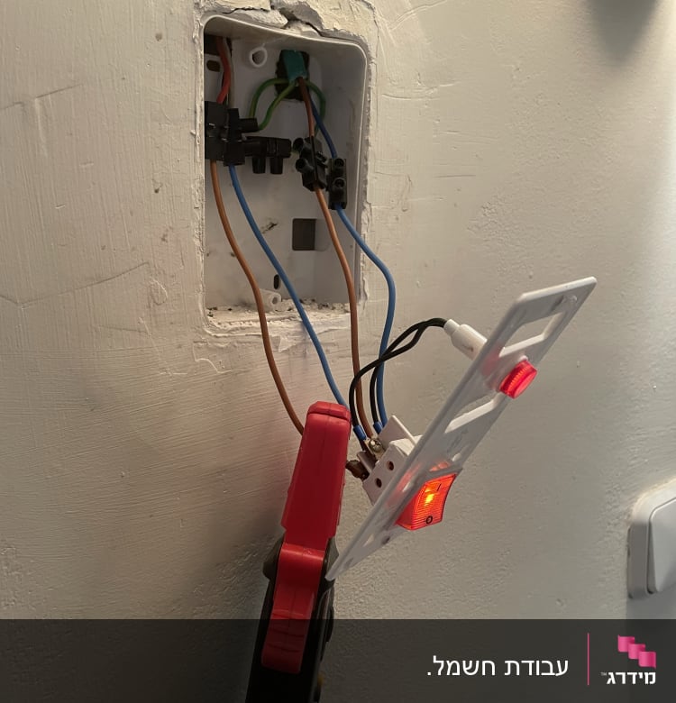 חוטי חשמל מחוברים לשקע בקיר עם כלי עבודה